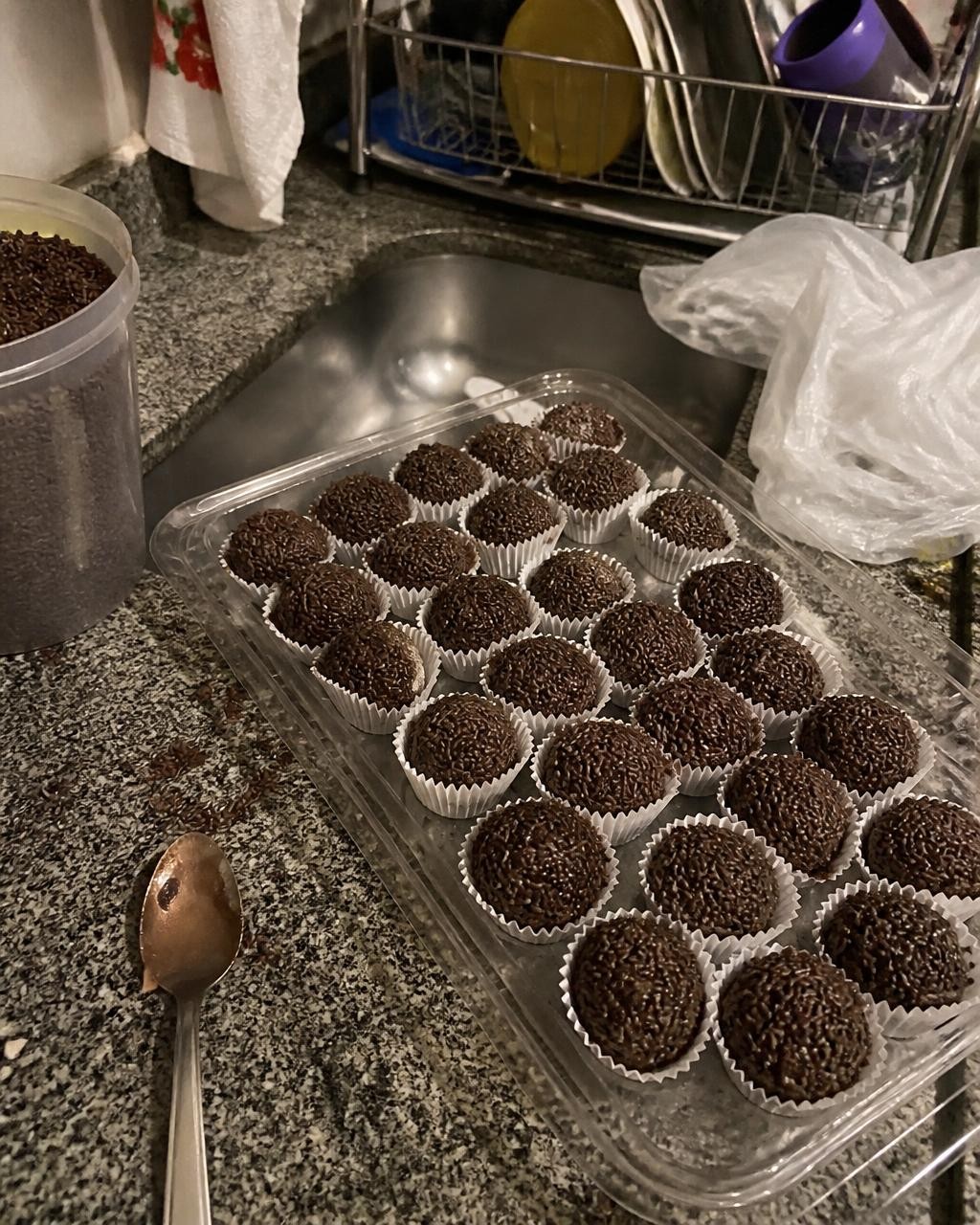 Foto dos brigadeiros na mesa da cozinha de casa, com a pia atrás