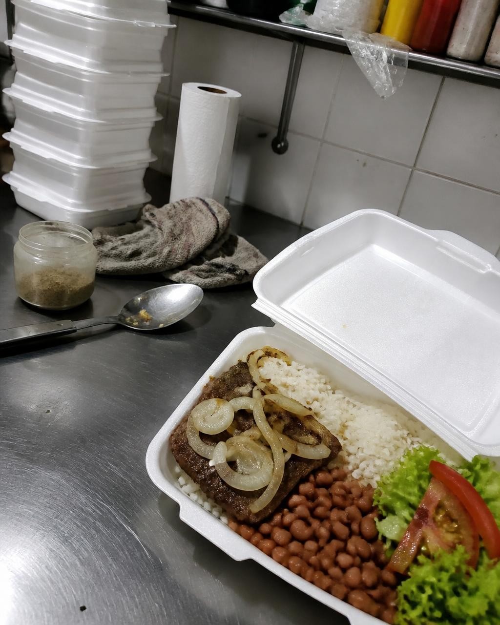 Foto crua de uma marmita no balcão bagunçado da cozinha, tirada de celular