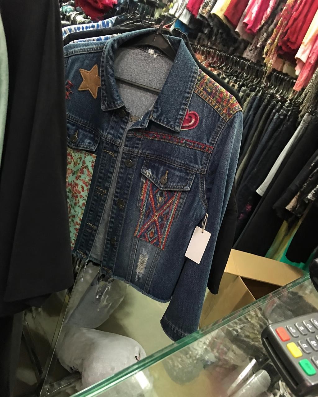 Foto da jaqueta jeans pendurada torta na arara lotada da loja
